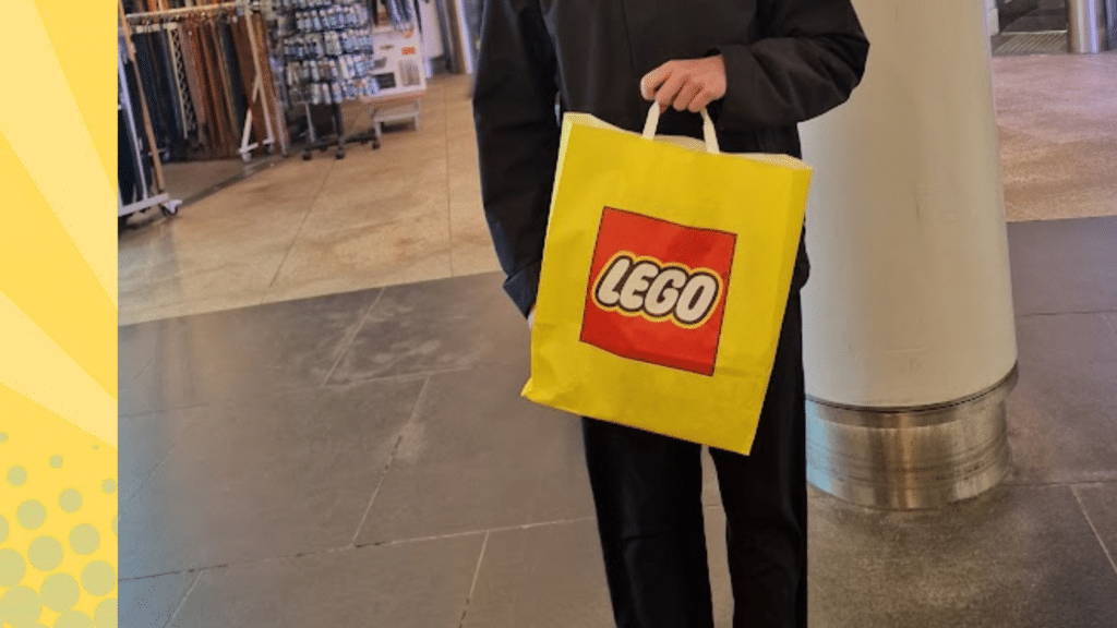 Iemand houdt een gele LEGO tas vast in een winkelcentrum
