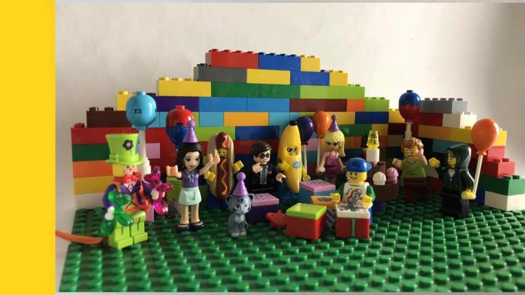 Verzameling LEGO minifiguren met feestthema op een groene basisplaat, inclusief clown, bananenpak en minidoll