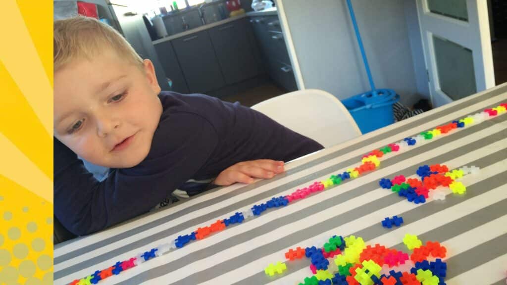 Kind bouwt een rij met kleurrijke Plus Plus Mini blokjes op tafel