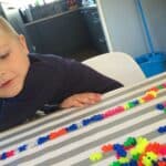 Kind bouwt een rij met kleurrijke Plus Plus Mini blokjes op tafel