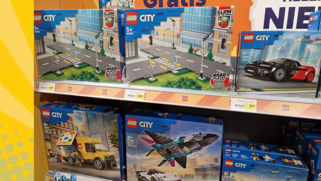 LEGO City sets in een winkelrek met prijskaartjes, waaronder wegplaten 60304 en EV Supercar 60486