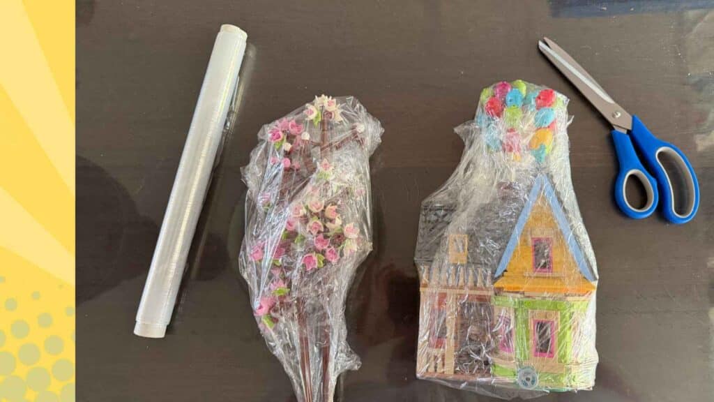 LEGO bouwwerken zoals het huis uit Up ingepakt in plasticfolie met een rol folie